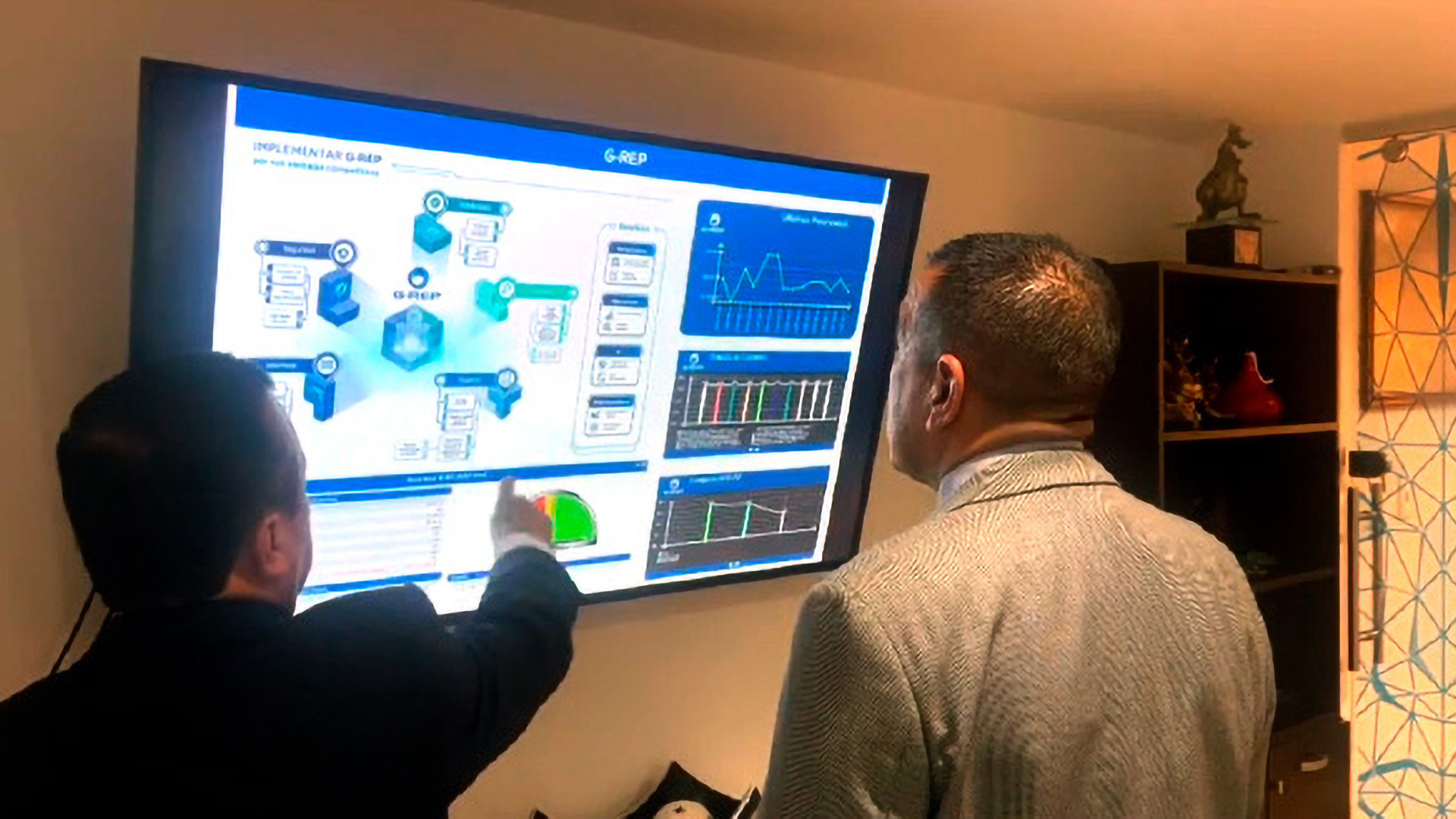 Oficinista señalando contenido de monitor con gráficas y diagramas de G-REP para analizar contenido junto a otro colega
